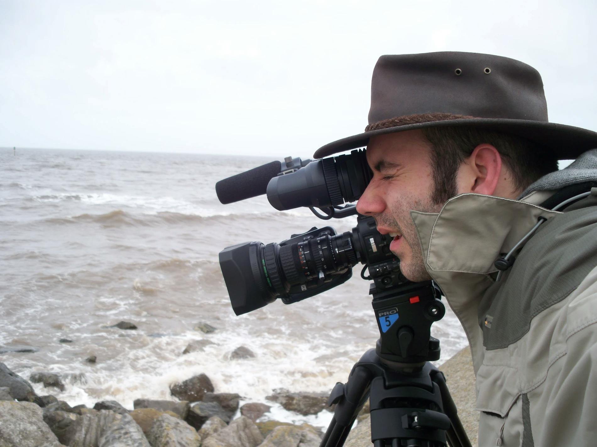 Cameraman shooting scene next to crashing waves of North Wales beach