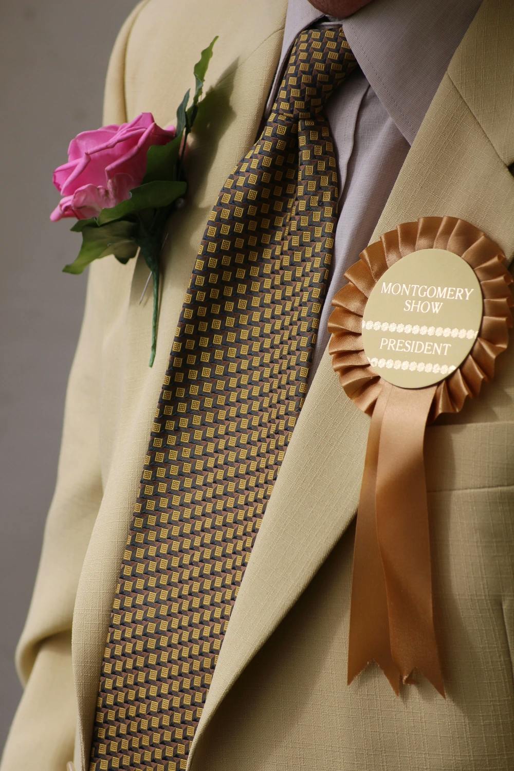 Older man wearing rosette showing he is a country show president